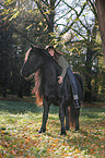 woman rides Frisian horse