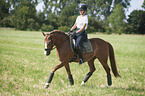 young woman rides German Riding Pony